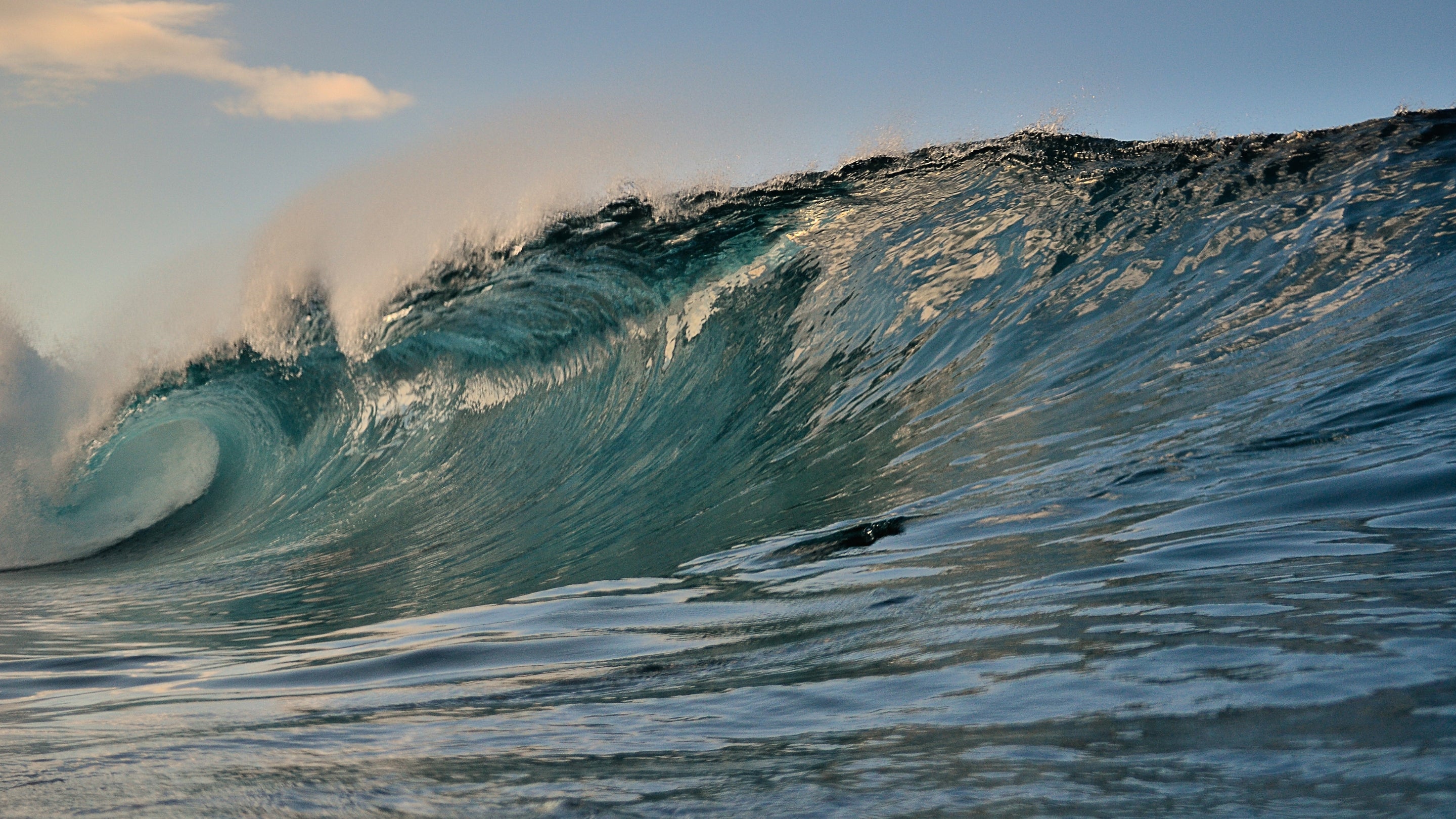 A large wave in the ocean with a clear sky.
