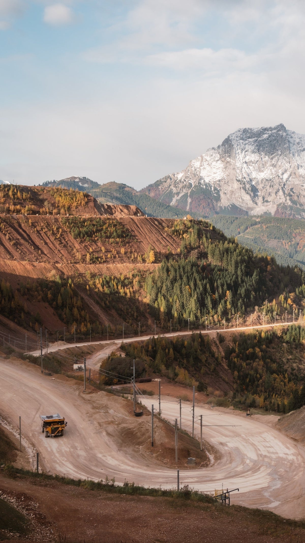 Winding road through a mountainous landscape with a large mountain in the background.