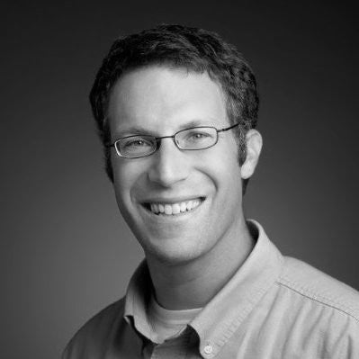 Black and white portrait of a man wearing glasses and a collared shirt.