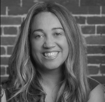 Black and white photo of a woman with a brick wall background
